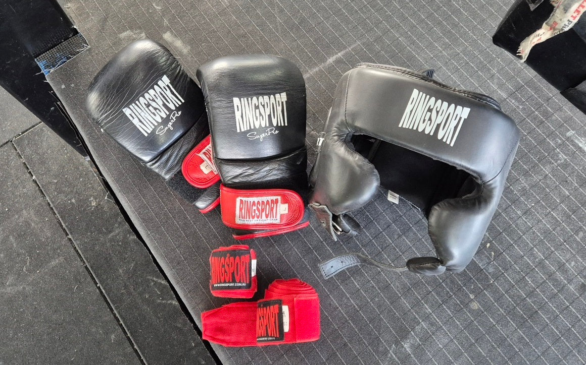 Ringsport boxing bag mitts drying on ring with hand wraps and head guard