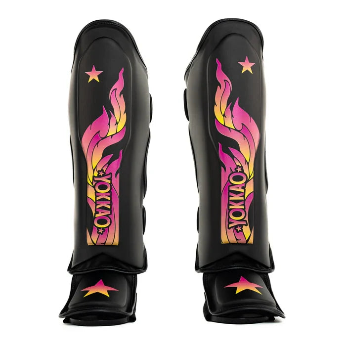 Yakkao black shin guards featuring a vibrant pink, yellow, and orange flame graphic 